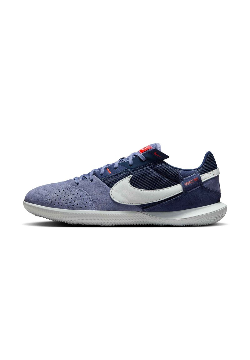 Jūras spēku un gaiši zilas sporta kurpes ar zamša un sieta materiāliem, kurām ir balts swoosh, teksturēti zoli un sarkanas akcenti uz mēles.