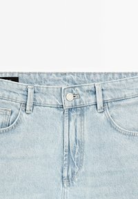 Light blue denim jeans with a button closure, five belt loops, and front pockets. Fabric has a smooth texture with subtle fading.