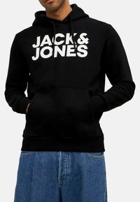Schwarzer Hoodie mit weißem "JACK & JONES" Logo, ausgestattet mit einer Kängurutasche, Kapuze mit Kordelzug sowie gerippten Bündchen und Saum. Aus Baumwollmaterial.