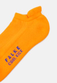 Calcetines de algodón naranja con una textura acanalada y un diseño de corte bajo. "FALKE COOL KICK" impreso en azul en el costado.