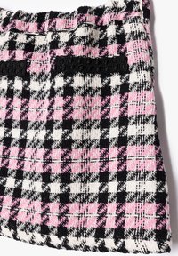 Gewebter Minirock mit einem schwarz-weißen und rosa karierter Muster. Besitzt einen strukturierten Stoff und einen elastischen Bund.