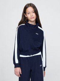 Námornícka modrá skrátená bunda na zips s bielymi bočnými pruhmi a logom "GAP"; skombinovaná s ladnými námorníckymi nohavicami. Jemná, textúrovaná látka.