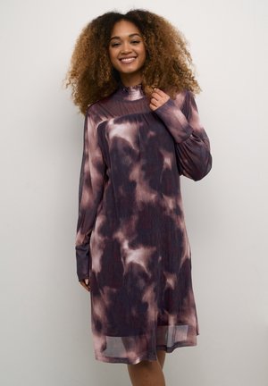 Pitkähihainen, tummat tähtikuviot omaava mekko purppuran ja vaaleanpunaisen sävyissä. Mekossa on korkea pääntie ja virtaava kangas, jossa on pleated-tekstuuri.