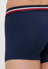 Boxers ajustés bleu marine avec une conception fitted, ceinture élastique avec des accents rayés rouges et blancs, et texture lisse.