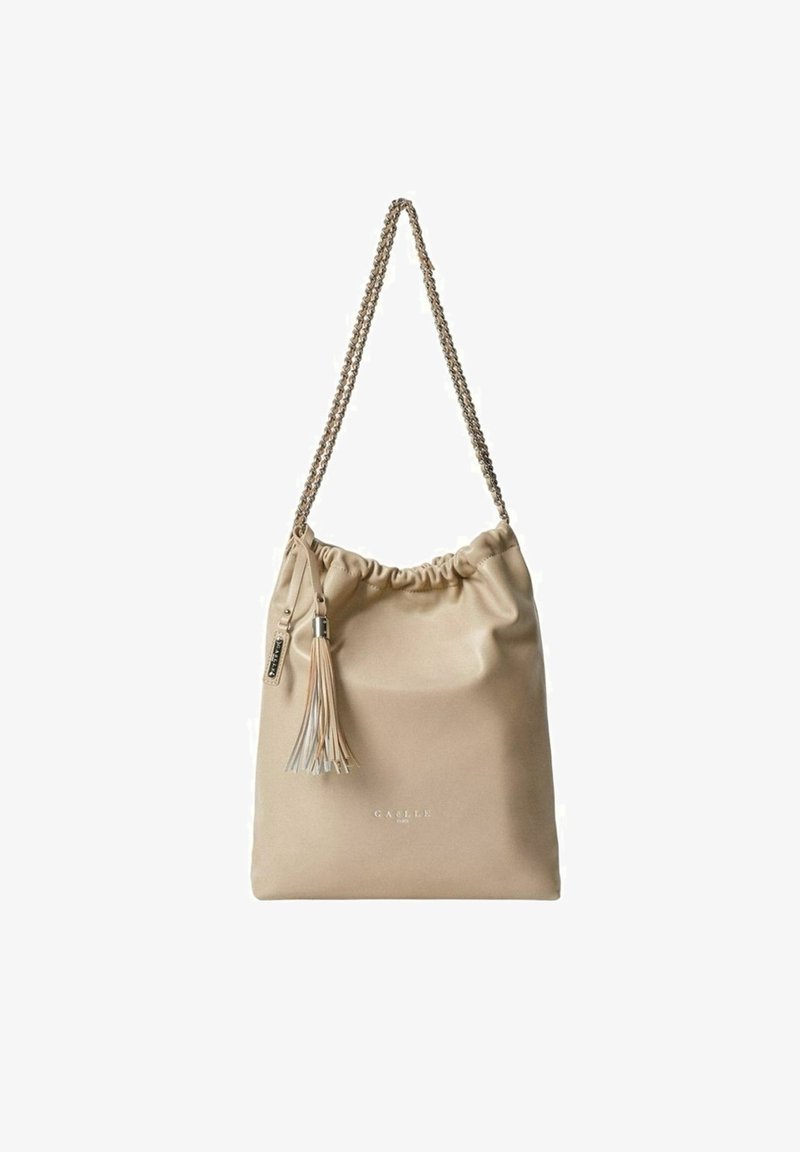 Sac à bandoulière en cuir beige avec fermeture à cordon, bandoulière en chaîne et un pompon décoratif. Présente une texture lisse et un marquage subtil.