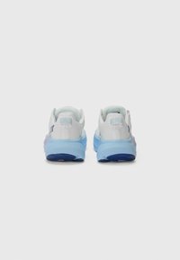 White athletic shoes with a gradient blue outsole, textured fabric, and a soft heel collar. The design features a subtle logo detail on the back.