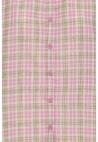 Chemise à carreaux roses présentant une combinaison de rayures roses, grises et brunes. Six boutons de fermeture avec des boutons rose clair et une texture de tissu douce.