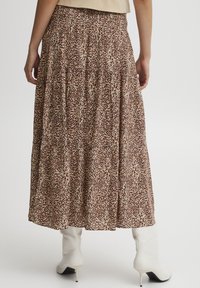 Gelaagde maxi rok in een bruin en beige dierenprint, met een gesmokte tailleband en zachte, vloeiende stof. Gestyled met witte hakken.