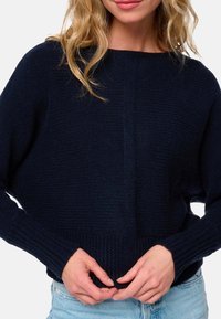 Marineblauer Strickpullover mit strukturiertem Muster, weitem Ausschnitt und gerippten Bündchen. Der Stoff wirkt dick und gemütlich.