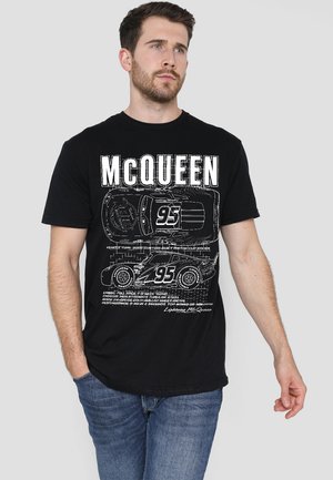 Black cotton t-shirt featuring graphic print of a car and text design, with "MCQUEEN" and technical details in white. Short sleeves, crew neck.