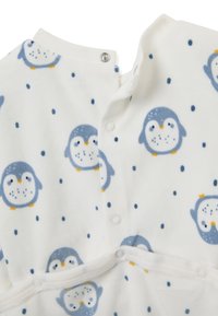 Prenda de forro polar blanca con un estampado de pingüinos en azul y amarillo, con cierres a presión en el cuello y un tejido suave y texturizado.