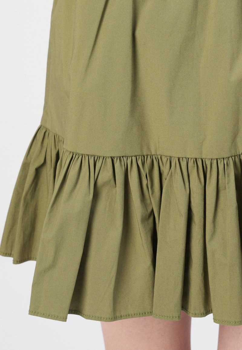 Abito in cotone verde oliva con orlo arricciato e texture plissettata. Tessuto morbido con un design semplice, senza motivi o hardware.