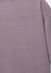 Lila sweatshirt met een ronde hals, zachte textuur en geborduurd logo op de borst. Heeft een losse pasvorm en korte mouwen.