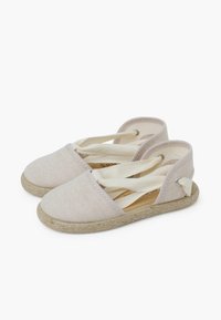 Espadrilles de tela beige claro con correas suaves, una suela de yute texturizada y acentos elásticos para un ajuste seguro. Forro interior suave.