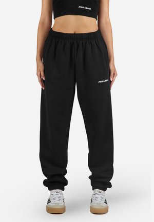 Zwarte trainingsbroek met een elastische tailleband en boorden, met witte "PEGADOR" tekst op de dij. Gemaakt van zachte, gestructureerde stof.