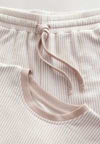 Lightweight, ribbed textile top and shorts in soft beige with thin white stripes, featuring a drawstring waist and a solid collar.