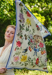 Gėlių šilko šalikėlis, puošiamas įvairiaspalviais gėlių, paukščių ir jauno elnio piešiniais, apsuptas mėlyno krašto ir sudėtingų raštų.