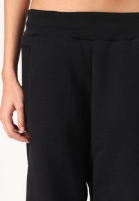 Sorte fleece joggebukser med ribbet liv, sidelommer og en glatt tekstur, skjært for en avslappet passform.