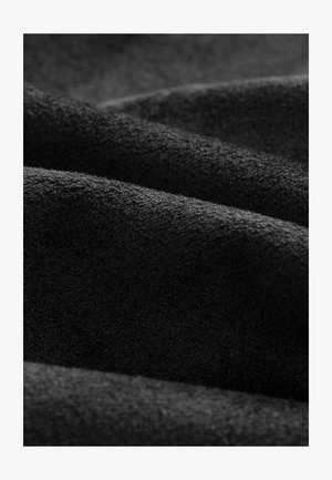 Black plush fabric with a soft texture, featuring folds and waves that create depth and a smooth, matte surface appearance.