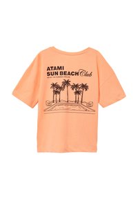 Korte mouwen, losvallend T-shirt van lichtoranje katoen. Heeft een zwarte grafische afbeelding van palmbomen en een zwembad met de tekst "ATAMI SUN BEACH Club."