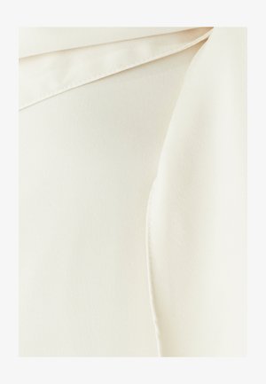 Blusa di colore crema con una texture liscia, simile al satin e un colletto piegato, caratterizzata da linee pulite e un leggero effetto lucido.