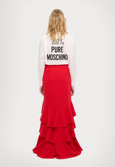Valge pikkade varrukatega särk musta tekstiga "100% PUHAS MOSCHINO" seljal, koos punase kihiliste volangidega seelikuga, sileda kangaga, hästi istuv talje.
