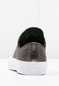 Baskets noires en mesh à enfiler avec un design texturé, dotées d'une semelle en caoutchouc blanche et du logo "Converse All Star" sur le talon.