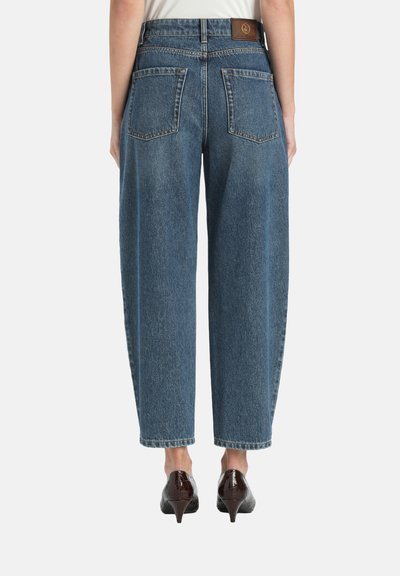 Blue denim wide-leg jeans with a high waist, two back pockets, and a brown leather patch at the waistband. Smooth texture and classic cut.