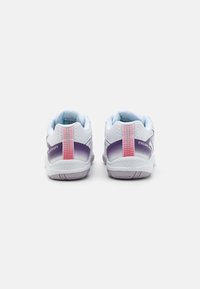Sportssko med en hvid mesh-overdel, der har en lilla gradient hæl, pink detaljer og en tekstureret bagklap for stabilitet og støtte.