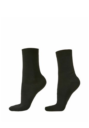 Paire de chaussettes noires unies longueur mollet, vues de côté sur fond blanc.