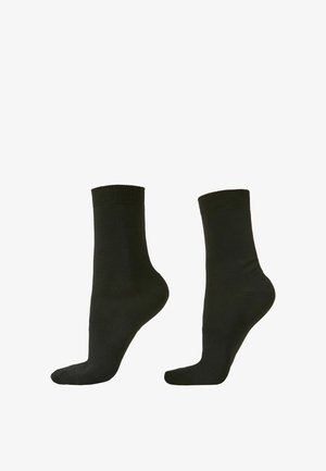 Paire de chaussettes noires unies longueur mollet, vues de côté sur fond blanc.