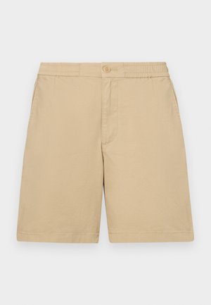 Shorts en coton beige avec une coupe régulière, taille élastique, fermetures à boutons et poches latérales. Texture lisse, design à mi-cuisses.