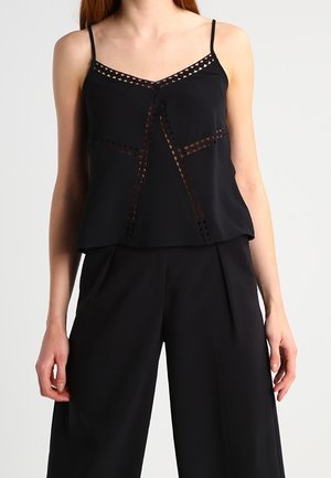 Black sleeveless top with a loose fit, featuring decorative lace cutouts along the neckline and front, made of smooth fabric.