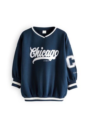 Sweat-shirt bleu marine avec inscription blanche « Chicago 1989 » sur le devant et un grand « C » blanc sur la manche gauche, poignets et ourlet côtelés.