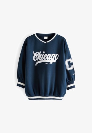 Marineblå sweatshirt med hvid "Chicago 1989" tekst på forsiden og et stort hvidt "C" på venstre ærme, ribstrikkede manchetter og kant.