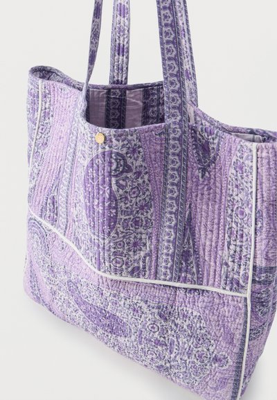 Sac fourre-tout matelassé avec des motifs cachemire et floraux violets, doté de deux bretelles et d'un passepoil blanc le long des bords.