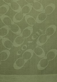 Tela verde con un patrón texturizado de círculos entrelazados en diferentes tonos de verde, que exhibe un diseño tejido y un acabado suave.