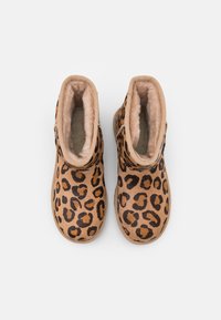 Leopard print ankle boots in tan and black, with a soft, fuzzy interior and a rounded toe design. Made from textured fabric.