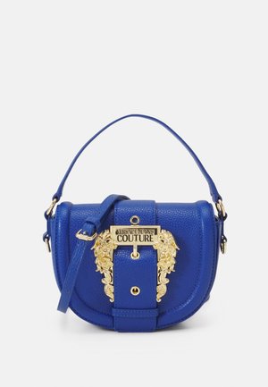 Mała niebieska skórzana torebka z górnym uchwytem, regulowanym paskiem i złotą dekoracyjną klamrą z napisem „Versace Jeans Couture.”