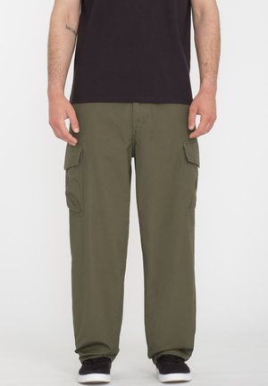 Olivenfarvede cargo bukser har flere sidelommer, en afslappet pasform og et let materiale. De er parret med en sort T-shirt og sneakers.