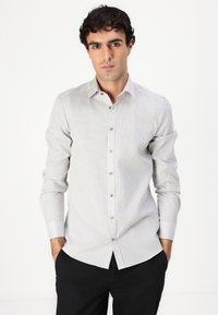 Light gray patterned shirt with a button-down collar and brown buttons, long sleeves, and a relaxed fit. Smooth fabric texture.
