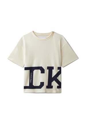 Kortermet kremfarget T-skjorte med store svarte "CK"-bokstaver og liten vertikal "Calvin Klein"-tekst nederst foran.