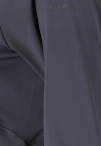 Herren Langarmshirt aus dunkelgrauem Stoff, mit glatter Textur, tailliertem Design und dezentem Logo-Detail nahe der Schulter.
