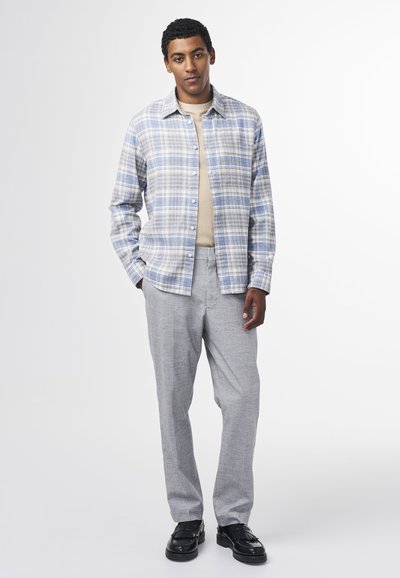 Plaid button-up shirt in blue and gray, paired with light gray trousers and black shoes. Soft fabric with button-down design.