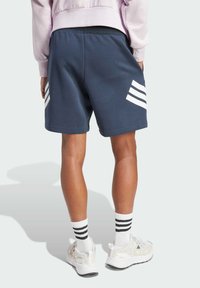 Navy blue athletic shorts with white stripe accents and an elastic waistband, paired with white socks featuring black stripes and light shoes.