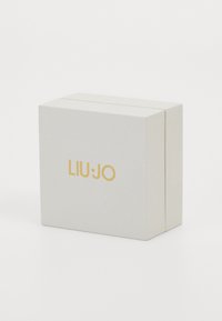 Hvit teksturert gaveeske med en gull "LIU·JO"-logo på forsiden. Esken har en enkel rektangulær form med en sikker lukking.