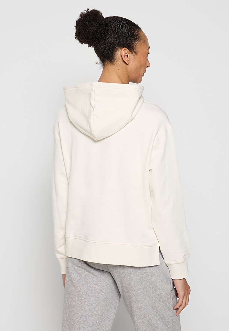 Hoodie color crema con cappuccio regolabile, maniche lunghe e vestibilità rilassata. Tessuto morbido con una finitura liscia e polsini a costine.
