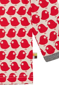 Motivo di uccelli rossi su tessuto beige chiaro, con polsino grigio e etichetta multicolore. Il design ripetuto presenta uccelli rotondi con grandi occhi.