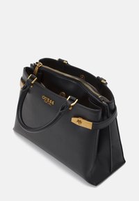 Czarna torebka wykonana z gładkiej sztucznej skóry, z elementami w kolorze złotym, podwójnymi uchwytami u góry oraz zapięciem na zamek. Z przodu znajduje się detal z logo.