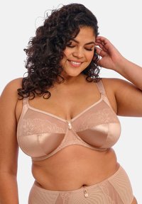 Beige pitsi- ja satiinirintaliivit, joissa on tuki ja koristeellinen etulukko sekä säädettävät olkaimet. Sujuva textura kukkakuviolla.